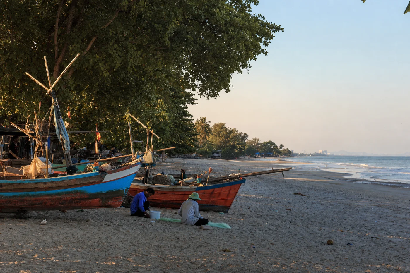 Quiet fishing village beach near Cha-Am with traditional wooden boats and tropical vegetation on a sunny afternoon